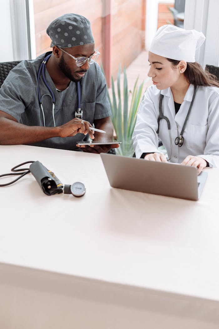 Two doctors discussing patient care with devices on a glass table indoors.